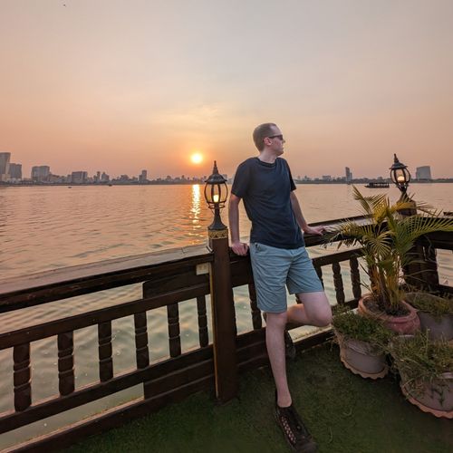 Lucas Silbernagel standing on a riverboat at sunset in Phnom Penh, Cambodia